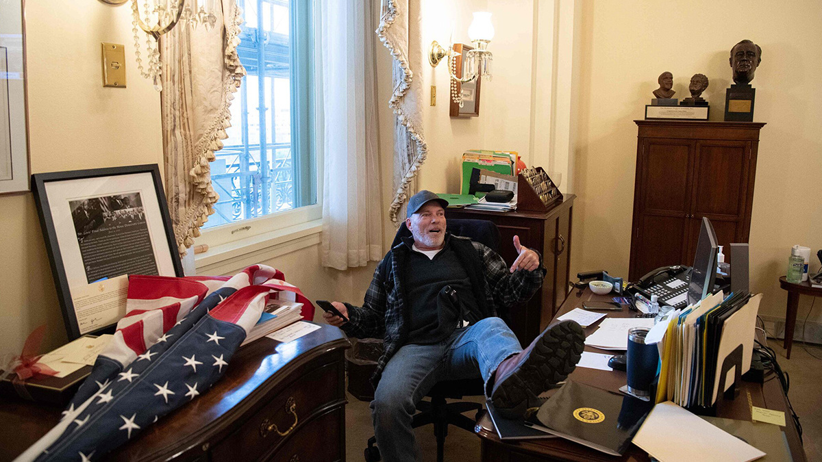 暴徒冲进了国会大厦之后，特朗普的支持者坐在议长南希·佩洛西的桌子上